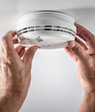 smoke alarm safety check man handling smoke alarm